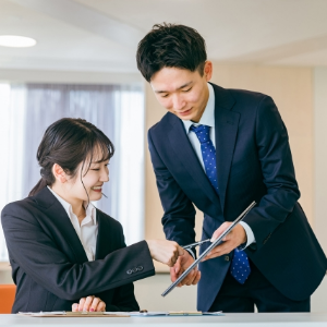 スーツ姿の男女二人が資料を元に話をしている様子