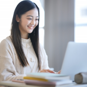 私服姿の女性がデスクでノートパソコンを操作している様子