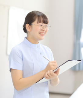 白衣姿の女性がバインダーとペンを持ち話をしている様子