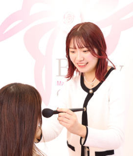 女性がメイクブラシを持ち1人の女性にメイクをしている様子